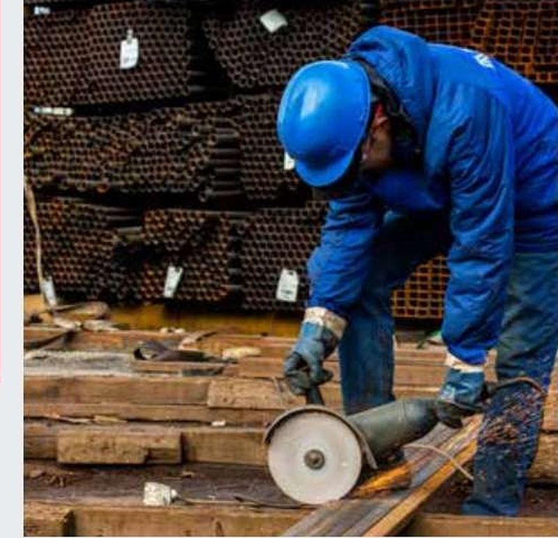 Operator cutting steel sections with an abrasive saw